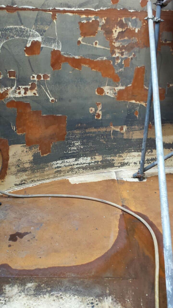 unevenly rusted chemical tank wall and flooring