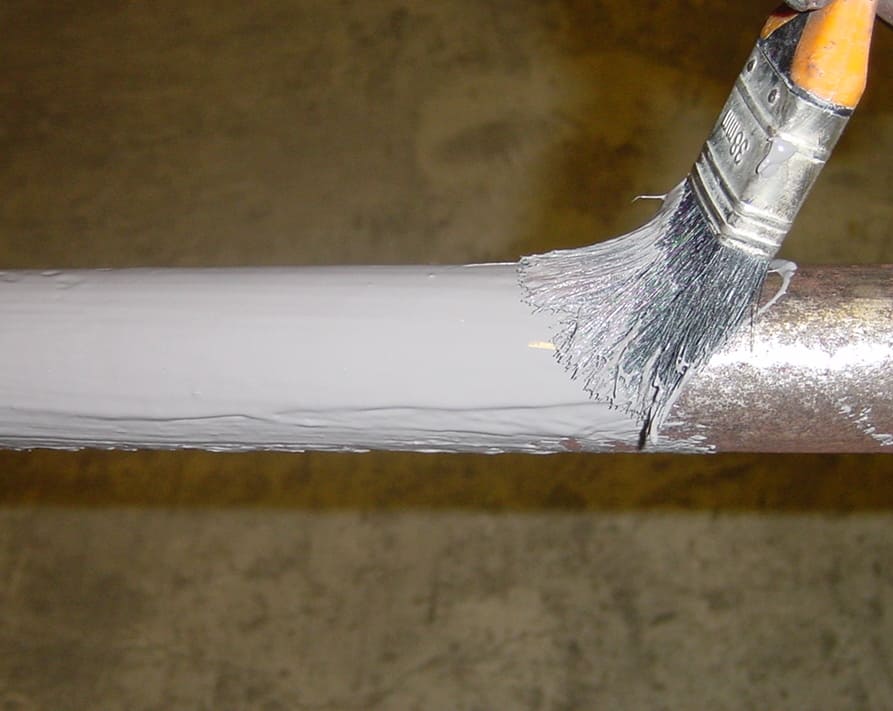 brush application of white paint to metal pipe