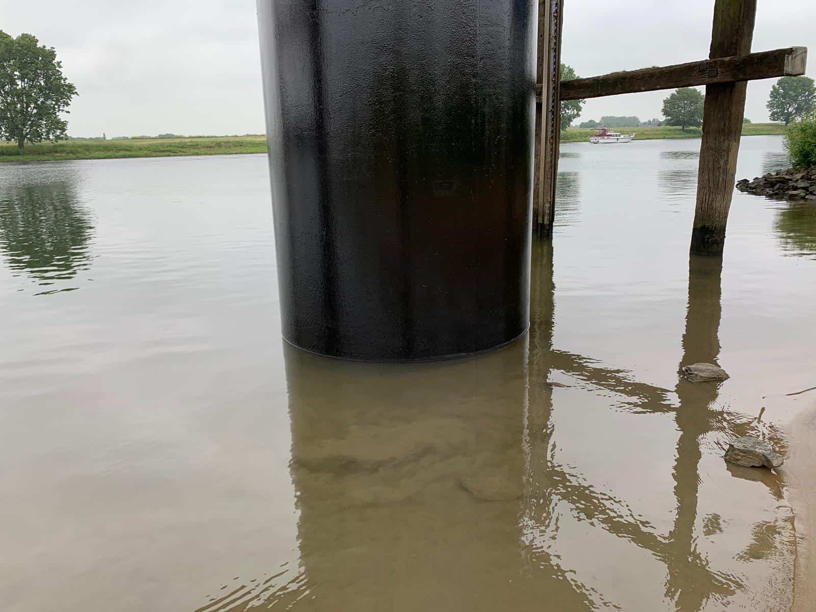close up of black freshly painted steel pile within water